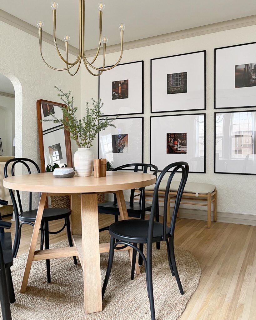 Round wooden dining toom table and black chairs, sitting on an oval rug.