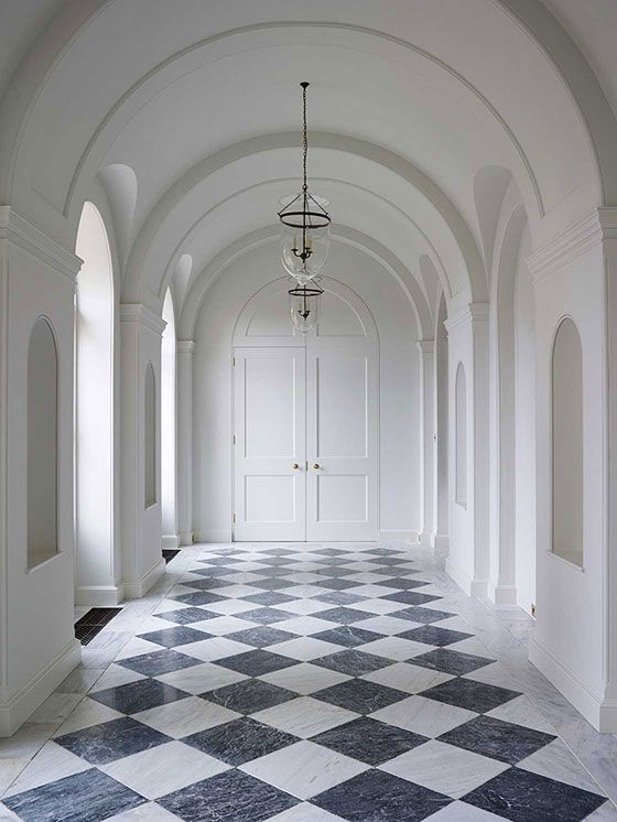An inspiration photo from Ben Pentreath of marble floors in a white arched hallway.