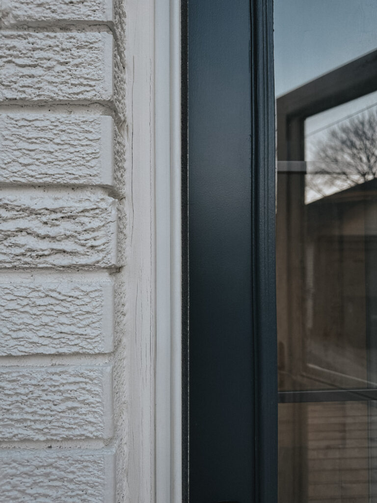Closeup photo showing the contrast between the off white brick color and the deep charcoal door color.