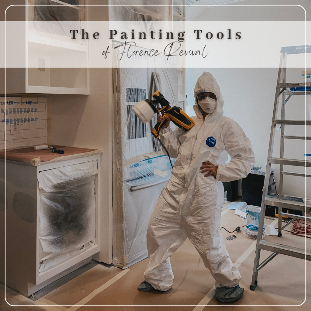 Image of Katie dressed in white coveralls holding a paint sprayer - in her kitchen as the cabinets are being painted.