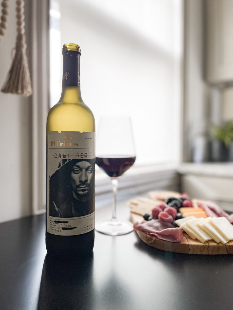 Image of wine bottle, glass of red wine, and charcuterie board.