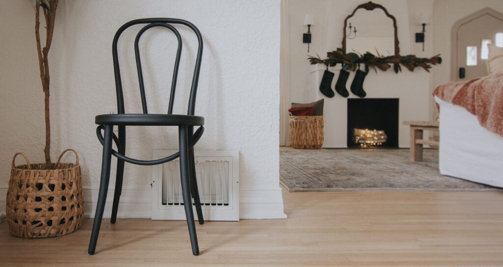 A black metal chair in the dining room, with a view of the living room in the background.